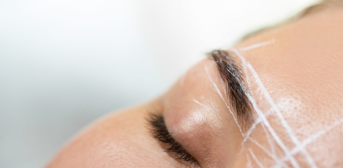 Closeup of female brow during professional eyebrow mapping procedure